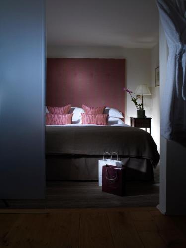 a bedroom with a large bed with pink pillows at Gidleigh Park- A Relais & Chateaux Hotel in Chagford