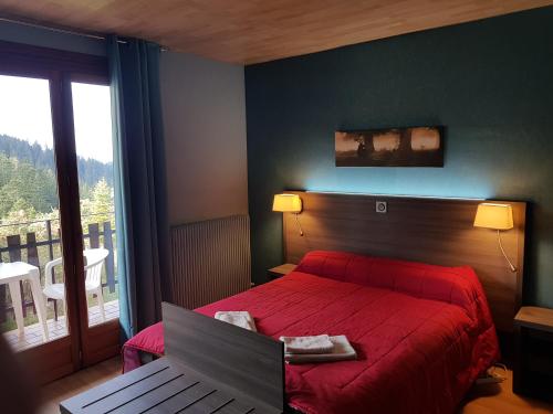 um quarto com uma cama vermelha e uma grande janela em Hôtel Les Chamois em La Bollène-Vésubie