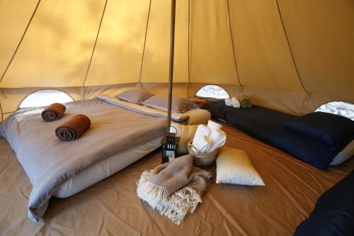 Camp 'Dvor' bell tent accommodation في Manjadvorci: سرير كبير في خيمة مع بطانيات ووسائد