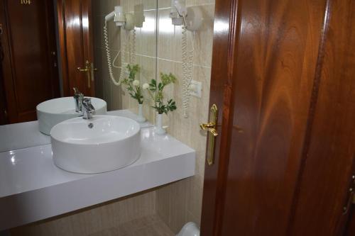 y baño con lavabo blanco y espejo. en Hotel Arvi, en Durrës