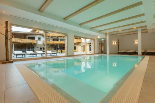 a large swimming pool with blue water in a building at das Chaletdorf - Pitztal in Sankt Leonhard im Pitztal