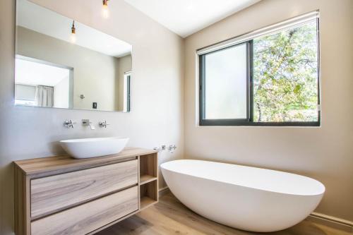 a bathroom with a large white tub and a sink at Hlangana Lodge in Oudtshoorn