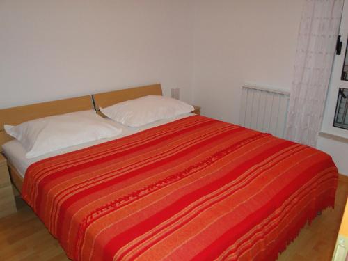 a bed with two pillows and a red striped blanket at Zele in Dolac