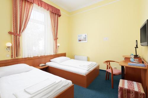 a hotel room with two beds and a television at Hotel Nikolas in Ostrava