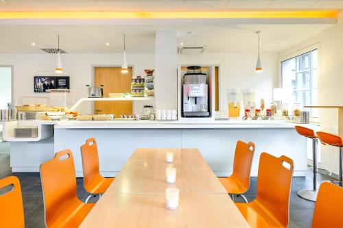 a dining room with a table and orange chairs at ibis budget Aachen City in Aachen