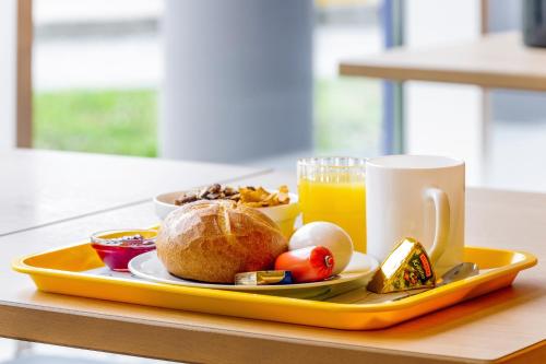 ein Tablett mit einem Teller Essen und einer Tasse Orangensaft in der Unterkunft CREO Halle Peissen in Peißen