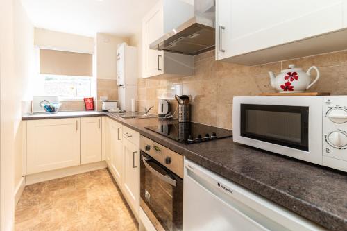 a kitchen with white cabinets and a microwave at Mycosy Provost Road in Dundee