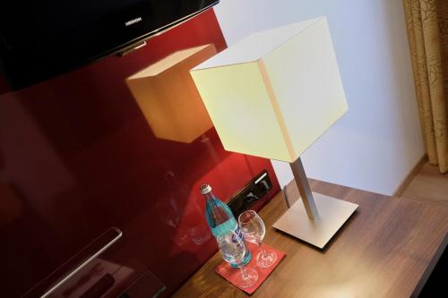 eine Lampe auf einem Tisch mit einer Flasche und einer Brille in der Unterkunft Romantica Hotel Blauer Hecht in Dinkelsbühl