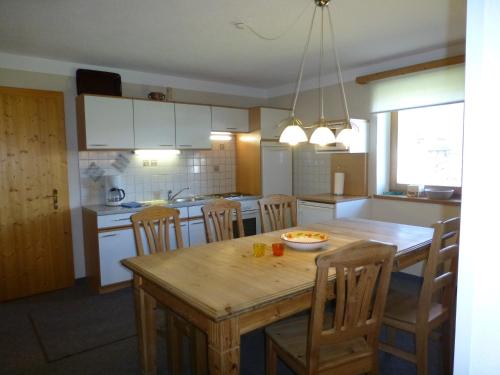 una cucina con tavolo in legno con sedie e una sala da pranzo di Apart Auszeit ad Arzl im Pitztal
