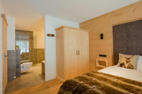 a bedroom with a large bed and a bathroom at das Chaletdorf - Pitztal in Sankt Leonhard im Pitztal