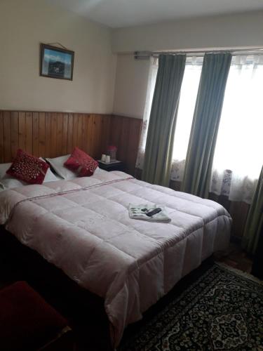 1 dormitorio con 1 cama blanca grande y ventanas en White Tara home stay, en Darjeeling