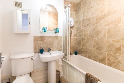 a bathroom with a toilet and a sink and a bath tub at Mycosyapartments54 in Paisley