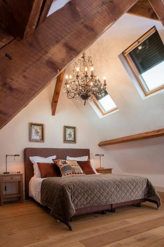 une chambre avec un grand lit et un lustre dans l'établissement Lalande-Laborie, à Auriac-du-Périgord