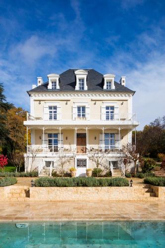 une grande maison blanche avec une piscine devant dans l'établissement Lalande-Laborie, à Auriac-du-Périgord