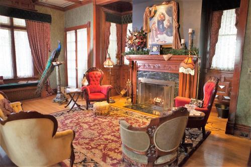a living room with a fireplace and red chairs at Alexander Mansion Bed & Breakfast in Winona