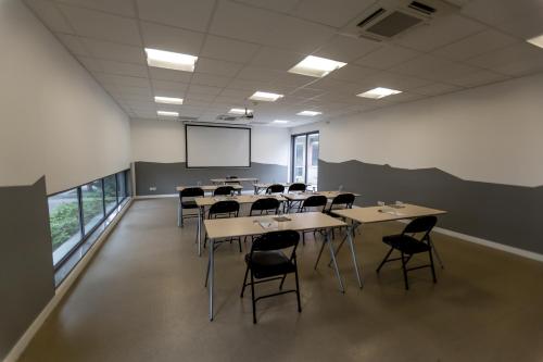 a classroom with tables and chairs and a projection screen at Kyriad Clermont-Ferrand-Sud - La Pardieu in Clermont-Ferrand