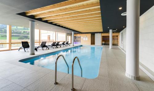 una piscina in un edificio con sedie intorno di TERRESENS - Les Fermes du Mont-Blanc a Combloux