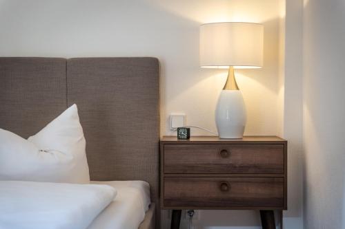 a lamp on a night stand next to a bed at Pension Kleiner König in Struppen-Siedlung