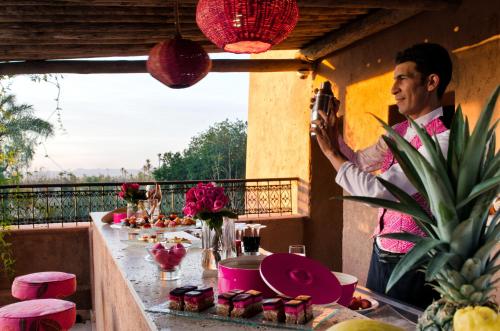 a man standing on a balcony with a table of food at Tigmiza Boutique Hotel & Spa in Marrakech