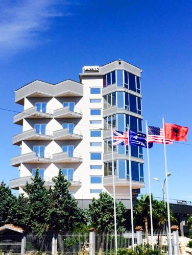 un edificio blanco con dos banderas americanas delante de él en Prince Hotel Fier, en Fier