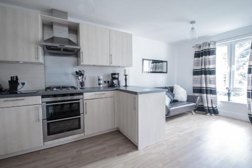 een keuken met witte kasten en een fornuis met oven bij Woodlands Luxury 4 Bedroom Townhouse Cults in Aberdeen