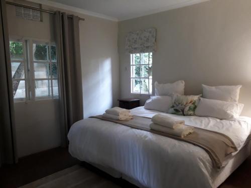 um quarto com uma cama grande com lençóis brancos e almofadas em Apartment Chapel Road em Hillcrest