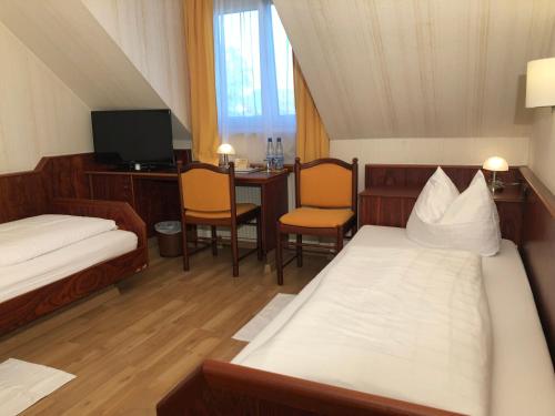 a room with two beds and a desk and a tv at Hotel-Restaurant und Gästehaus Löwen in Süßen