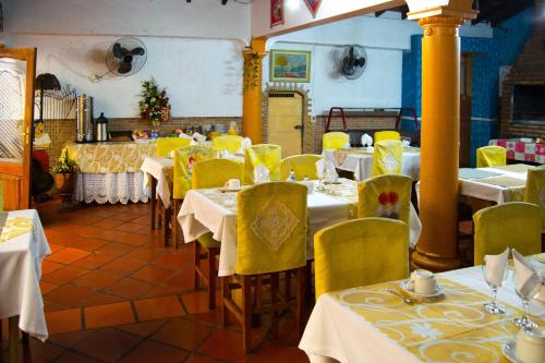 a restaurant with tables and chairs with yellow chairs and tablesktop at Hotel & Restaurante Guarania in Ciudad del Este