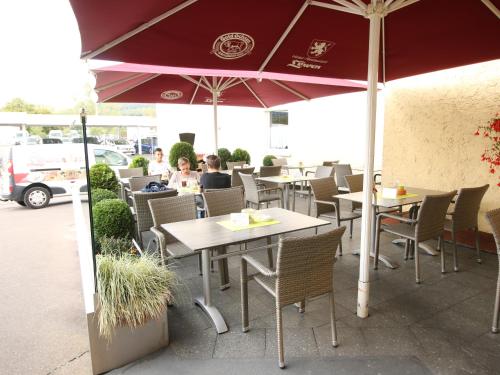 a restaurant with tables and chairs and an umbrella at Hotel-Restaurant und Gästehaus Löwen in Süßen