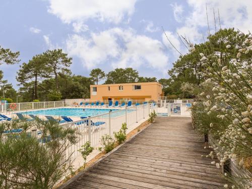 une passerelle en bois menant à une piscine dans l'établissement Residence Les Grands Pins - maeva Home, à Carcans