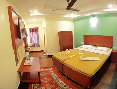a bedroom with a large bed with a yellow blanket at Siva Guest House in Mahabalipuram