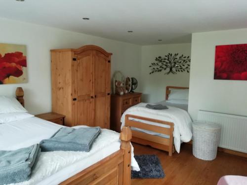 1 dormitorio con 2 camas y armario de madera en Brown Cow Cottage, en Dalton-in-Furness