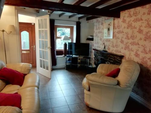 a living room with two couches and a television at Brown Cow Cottage in Dalton in Furness