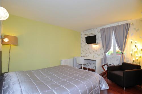 a bedroom with a bed and a chair and a desk at Logis Aux Maisons in Maisons-lès-Chaource
