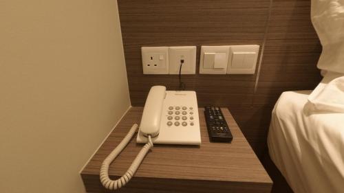a phone sitting on a table next to a bed at U Design Hotel Kuala Lipis in Kuala Lipis