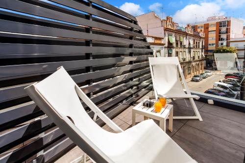 two white chairs and a painting on a balcony at Catalonia Giralda in Seville
