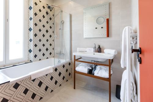 a bathroom with a tub and a sink and a shower at Hotel Verlaine in Cannes