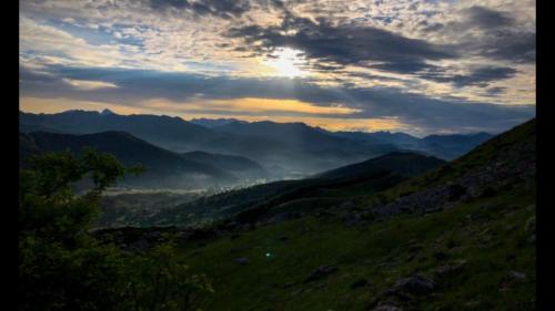 a view of a mountain valley with the sun setting at La Era in Lario