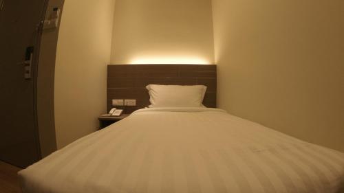 a bedroom with a white bed with a night stand at U Design Hotel Kuala Lipis in Kuala Lipis