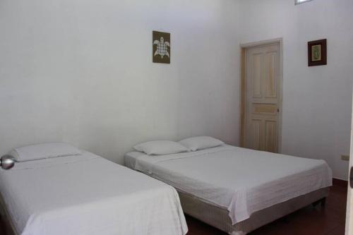 two beds in a room with white walls at Casa San José in El Conacaste