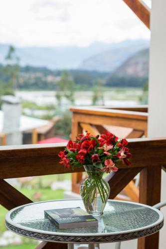 a glass vase with red flowers on a glass table at Intiterra Apart Hotel Villas in Urubamba