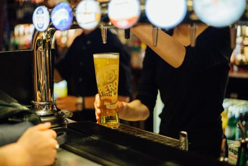 a man holding a glass of beer at a bar at Kings Arms Hotel in Berkhamsted
