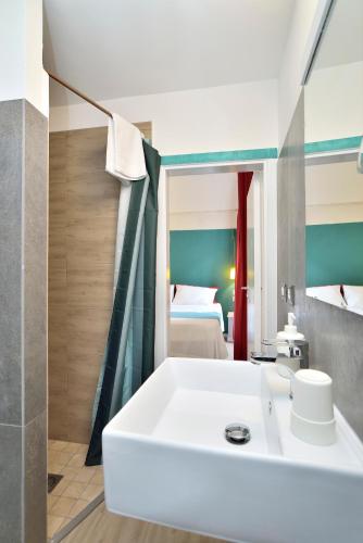 a bathroom with a white sink and a bedroom at Modica Old Town Rooms in Modica