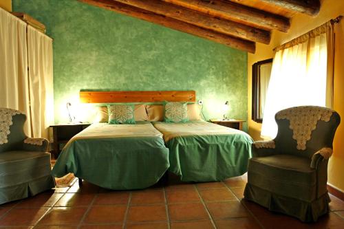 a bedroom with a bed and two chairs at Casa Oliban in Arbaniés