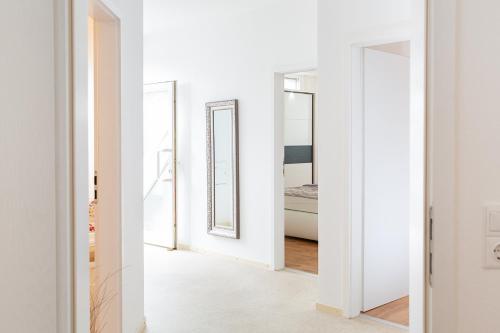 a hallway with three mirrors in a white room at Holidayapartment Rüsselsheim in Rüsselsheim