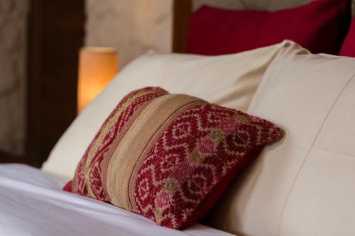 a red pillow sitting on top of a bed at Intiterra Apart Hotel Villas in Urubamba