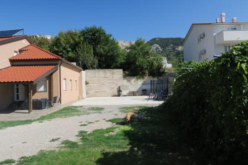 a view of a yard with a house and a building at Family Apartment in Baška