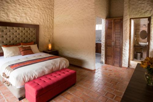 a bedroom with a large bed and a red bench at Intiterra Apart Hotel Villas in Urubamba