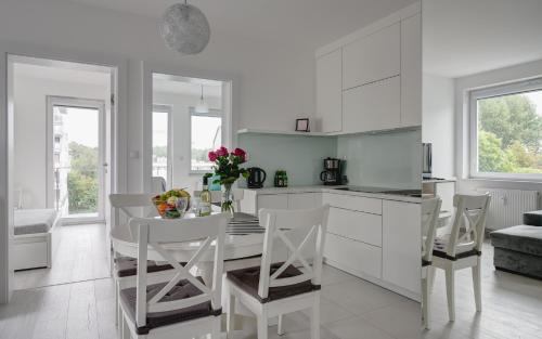 kuchnia z białymi szafkami oraz stołem i krzesłami w obiekcie ApartamentyPrzyMorzu Bliżej Morza z 3 sypialniami w Kołobrzegu