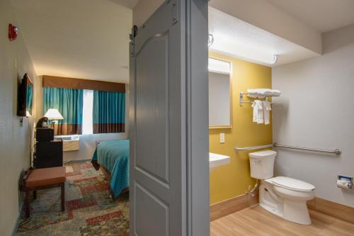 a bathroom with a sink and a toilet and a bed at Vagabond Inn Executive Hayward in Hayward